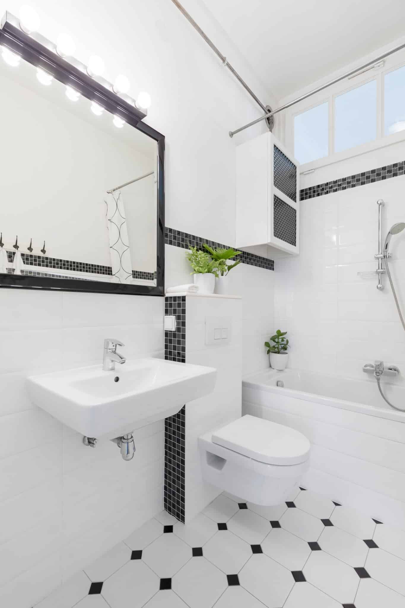 Mirror above washbasin in black and white bathroom interior with toilet and bathtub. Real photo