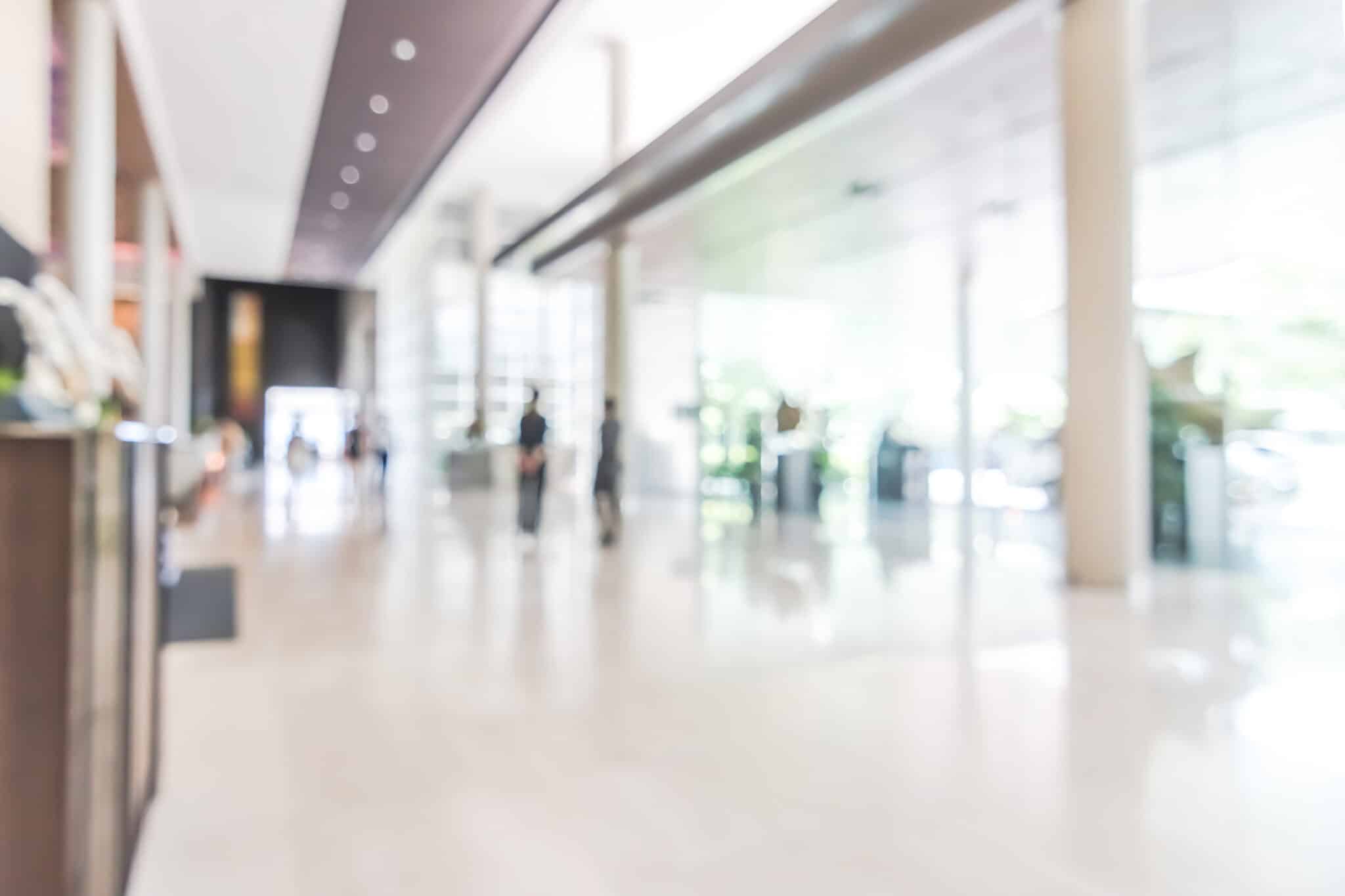 Hotel or office building lobby blur background interior view toward reception hall, modern luxury white room space with blurry corridor and building glass wall window