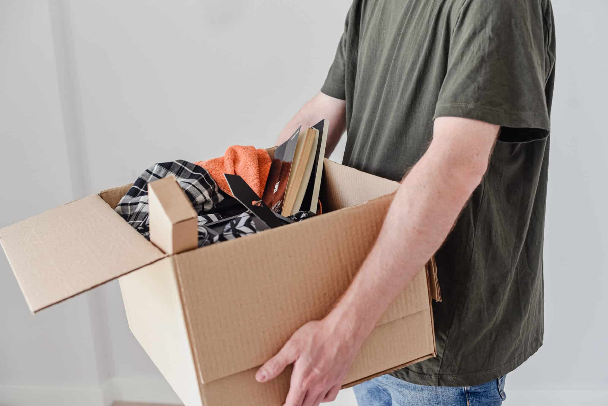 young man holds a moving box Limpieza del hogar en familia